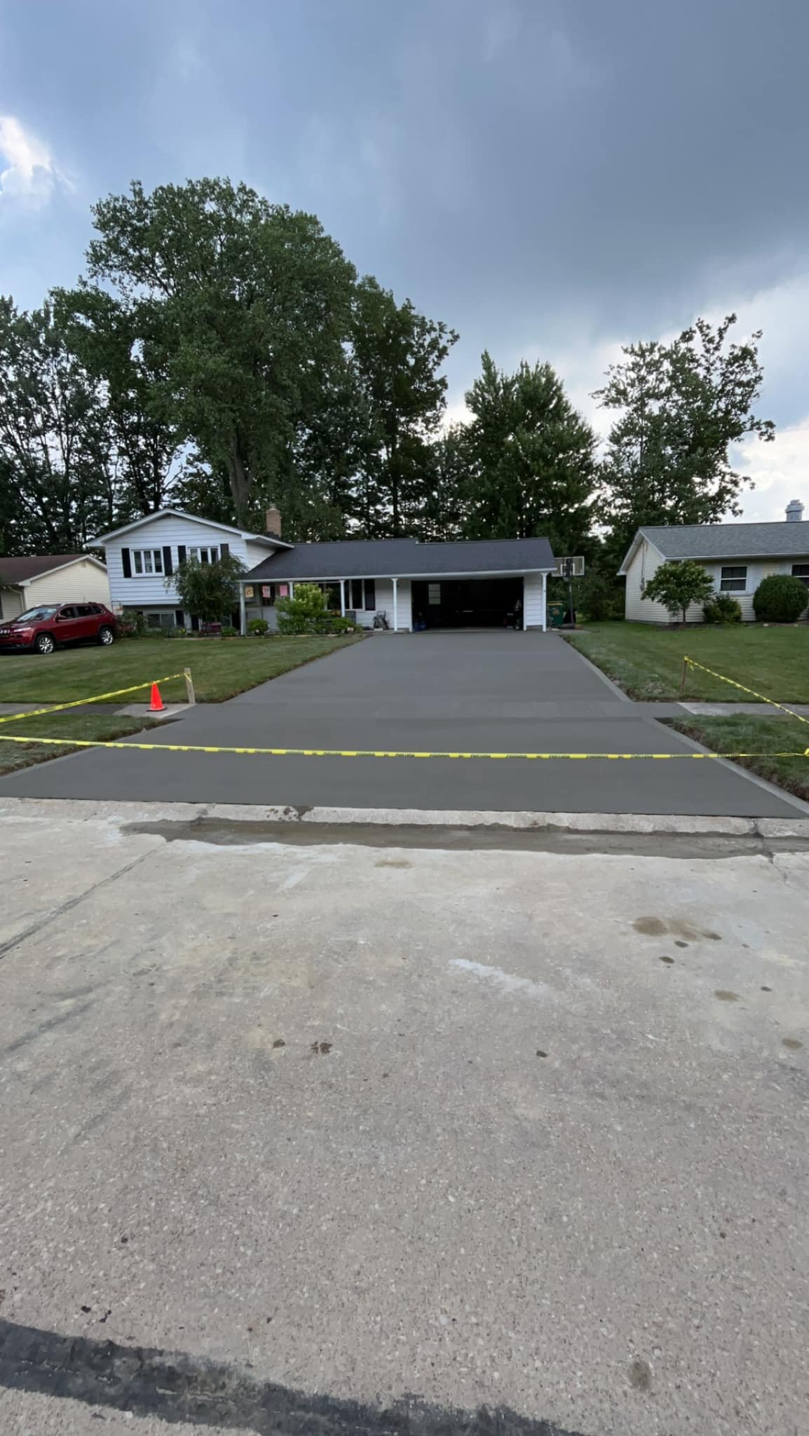 A new concrete driveway by Xpress Construction & Services is safely marked, showing careful work in a neat suburban setting.