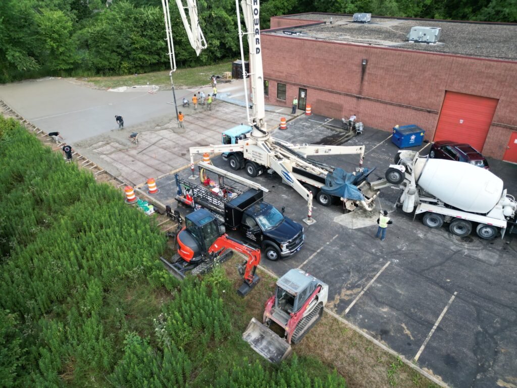 Xpress Construction & Services workers pour concrete, showing teamwork and progress at a busy building project.